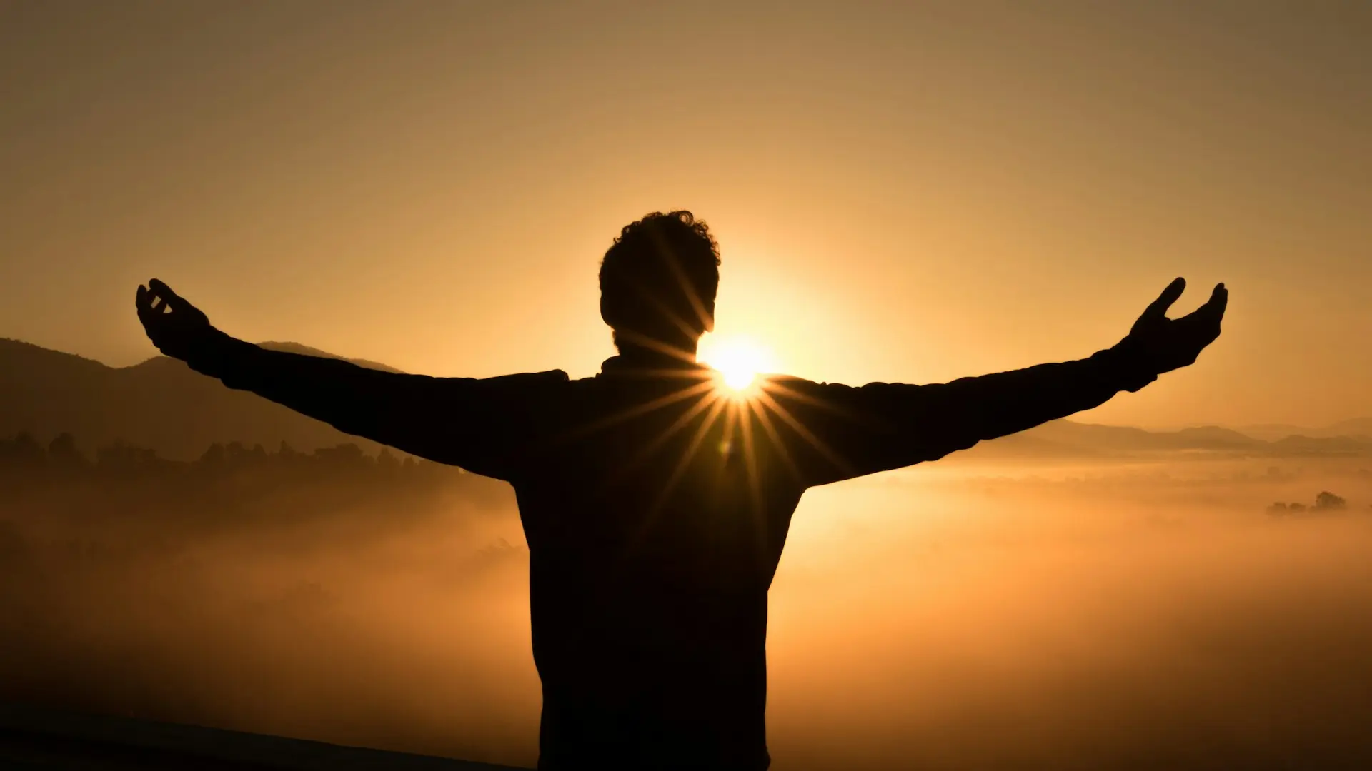 silhouette photo of man on cliff during sunset